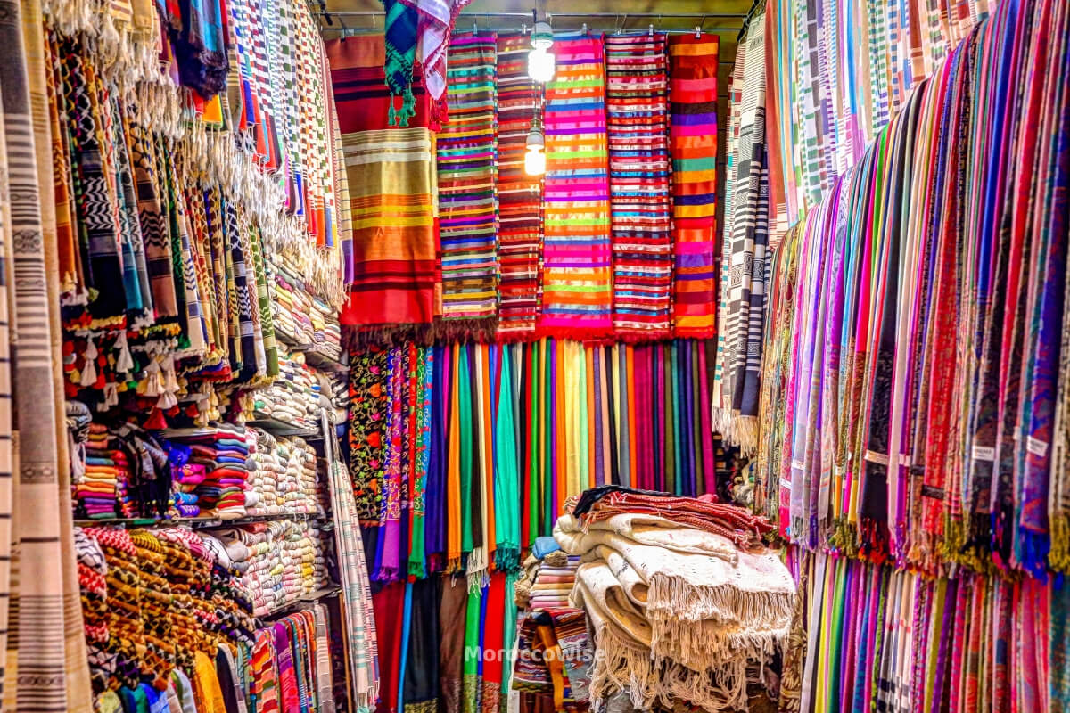 A shopper browsing colorful textiles in a souk